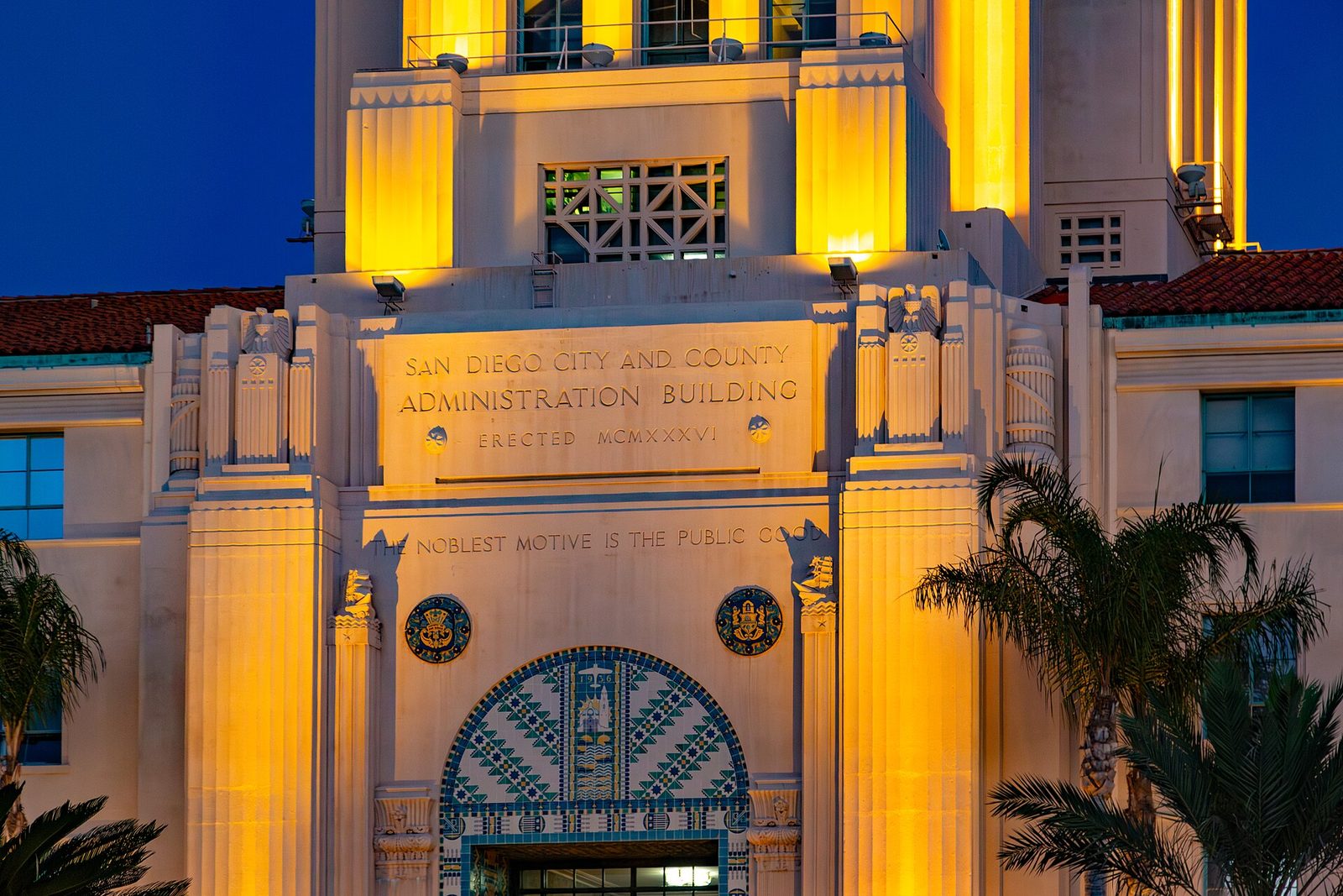 The San Diego City and County Administration Building at dusk. The county's motto is carved over the door: the noblest motive is the public good.