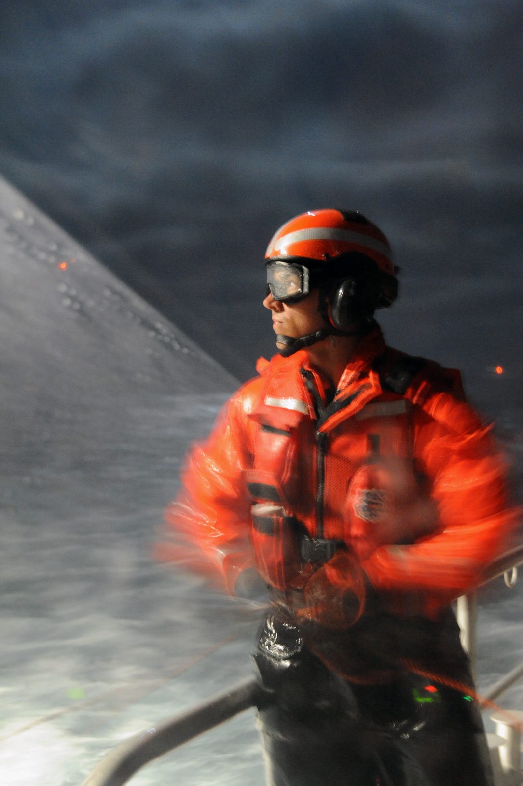 A Coast Guard Station San Diego crewman tends a line in heavy spray during a night exercise. On Sunday, a Station San Diego boat crew located the grounded sailboat but could not approach it in the shallow, hazardous water.