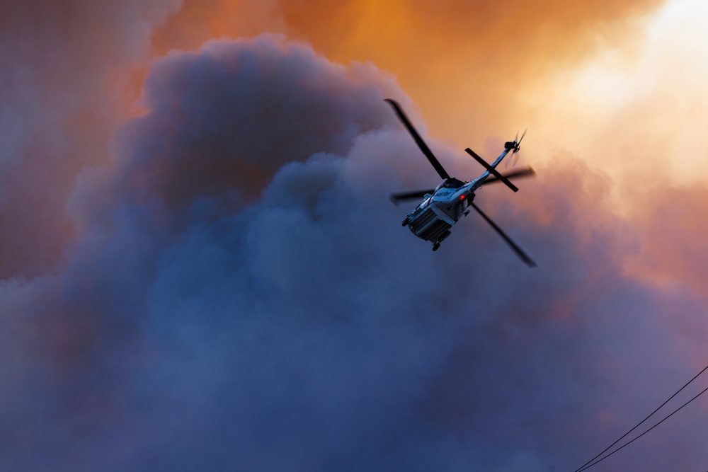 A firefighting helicopter flies through the Henderson Fire smoke column at Camp Pendleton on Thursday evening. Air and ground units from Cal Fire and the U.S. Forest Service supported the Camp Pendleton Fire Department through the evening.