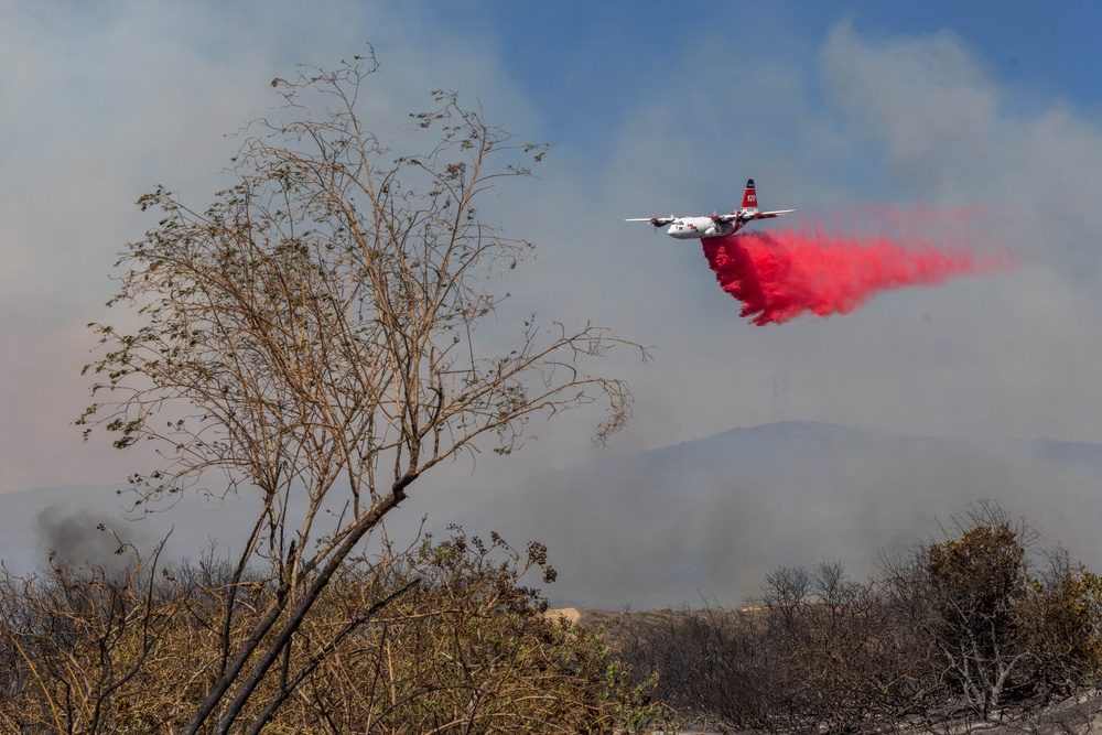 A Cal Fire C-130 air tanker drops retardant over the Henderson Fire at Camp Pendleton on Friday morning, October 16. Camp Pendleton crews worked the fire with air and ground units from Cal Fire and other agencies through the morning.