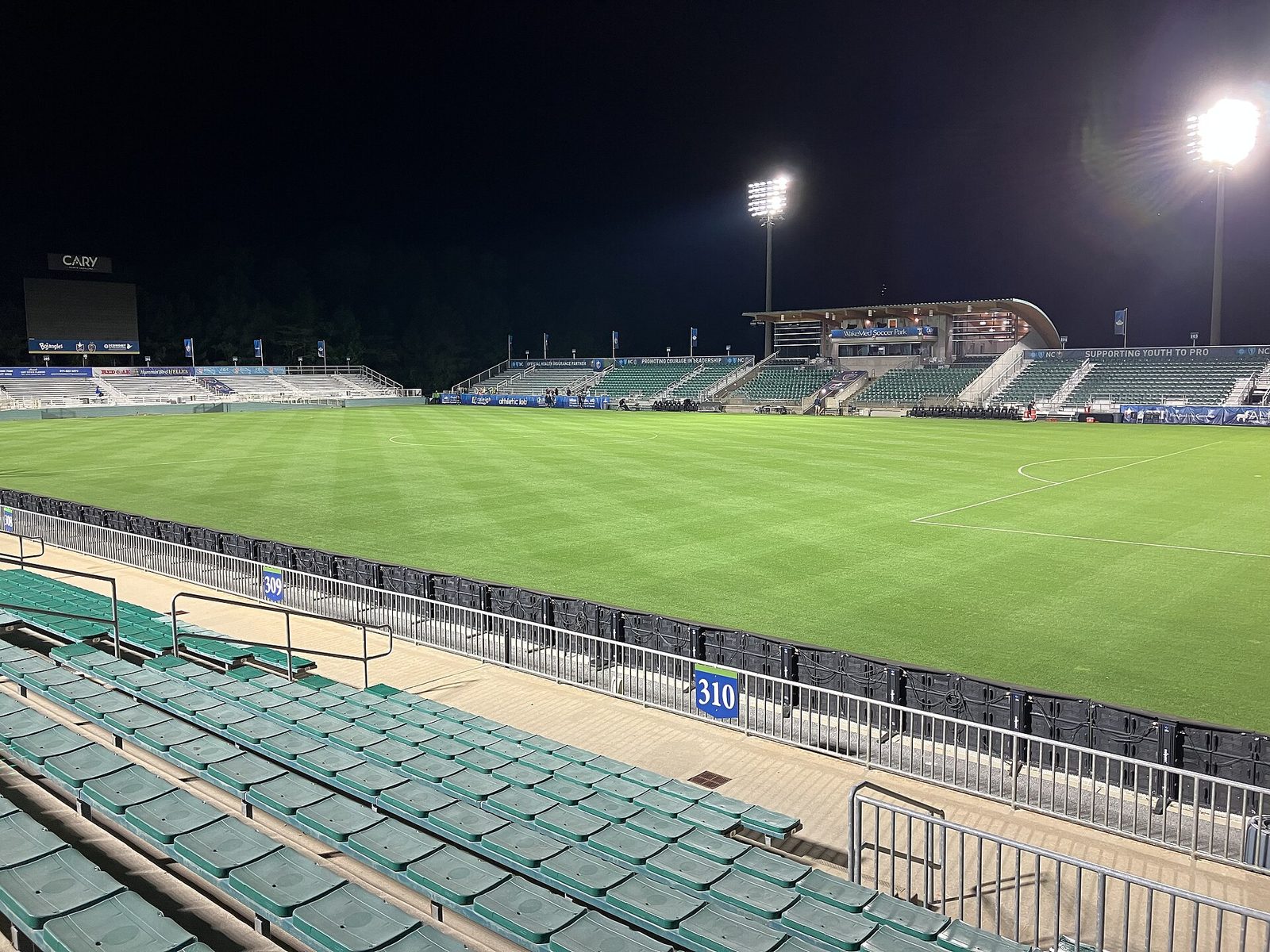 The stadium at WakeMed Soccer Park under the lights, with the Cary sign beyond the far stand. The Wave's win here means its next playoff match is at home: a quarterfinal at Snapdragon Stadium between November 6 and 8.